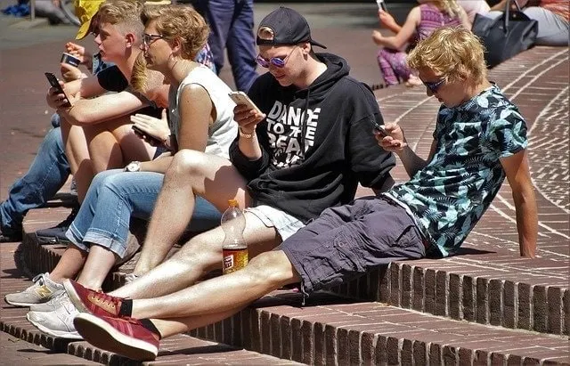 青少年使用行動裝置坐在外面的台階上