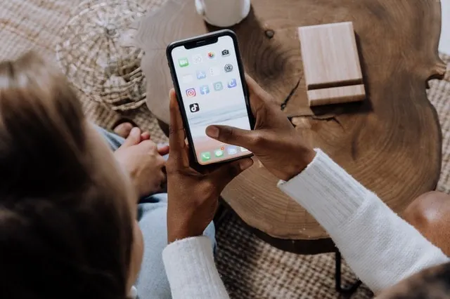 Zwei Menschen halten ein Telefon und klicken auf das TikTok-Symbol