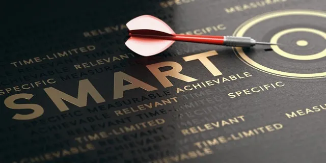 Fléchette s'approchant de l'œil de bœuf d'une cible sur un fond comportant divers mots liés aux objectifs SMART.