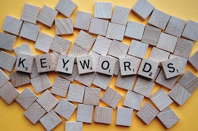 Blocs de lettres de Scrabble qui épellent des mots-clés entourés de blocs de lettres vierges.
