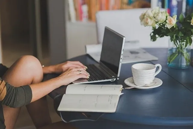 Person tippt auf einem Laptop an einem Tisch