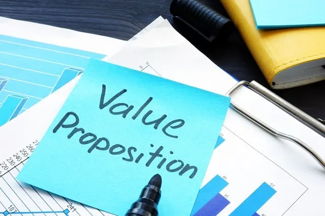Note autocollante avec "Proposition de valeur" sur un presse-papiers avec des papiers.