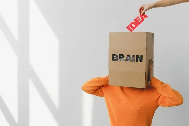 Placer à la main le mot "IDEA" dans une boîte qui dit "BRAIN" sur la tête d'une personne.