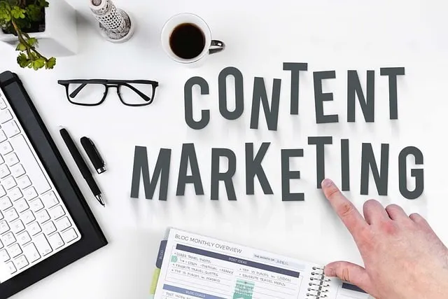 Mano che indica le parole content marketing su un tavolo con un taccuino e una tastiera