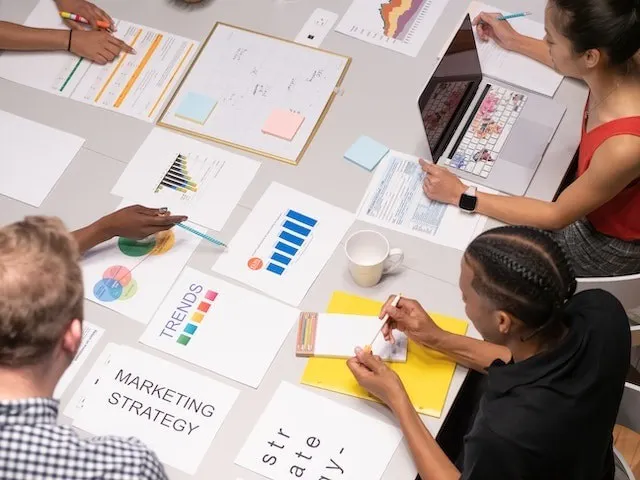 Il team di marketing esamina le analisi e lavora alla strategia di marketing intorno a un tavolo